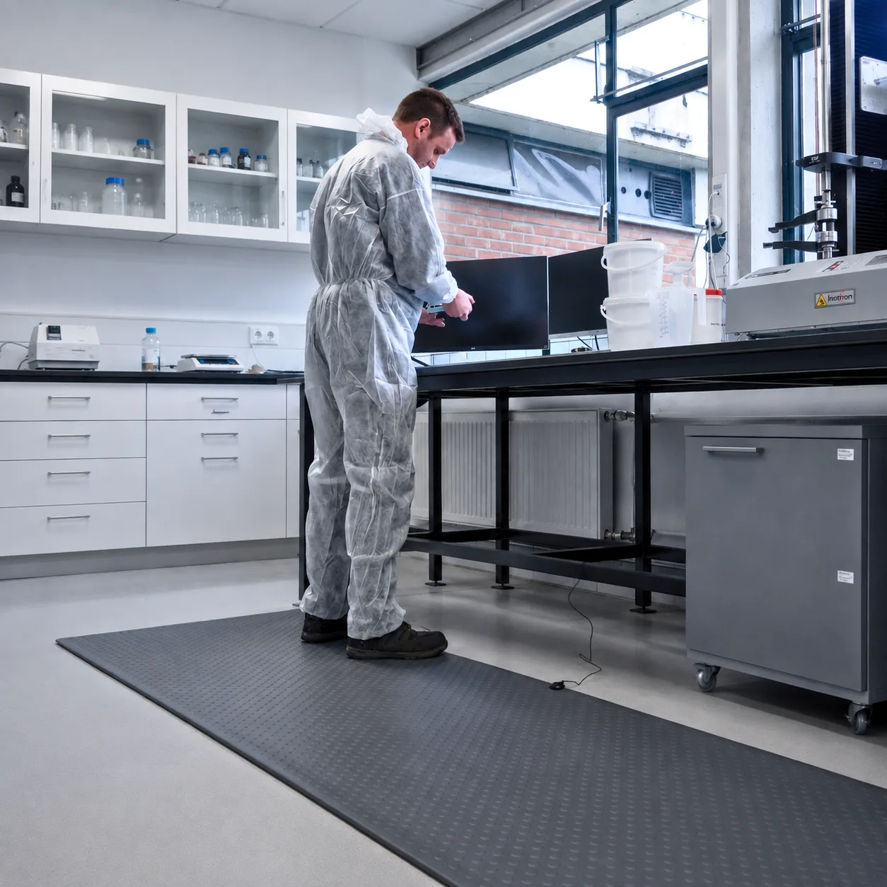 M4 grey ESD floor mat at a laboratory bench with an operator in cleanroom overalls