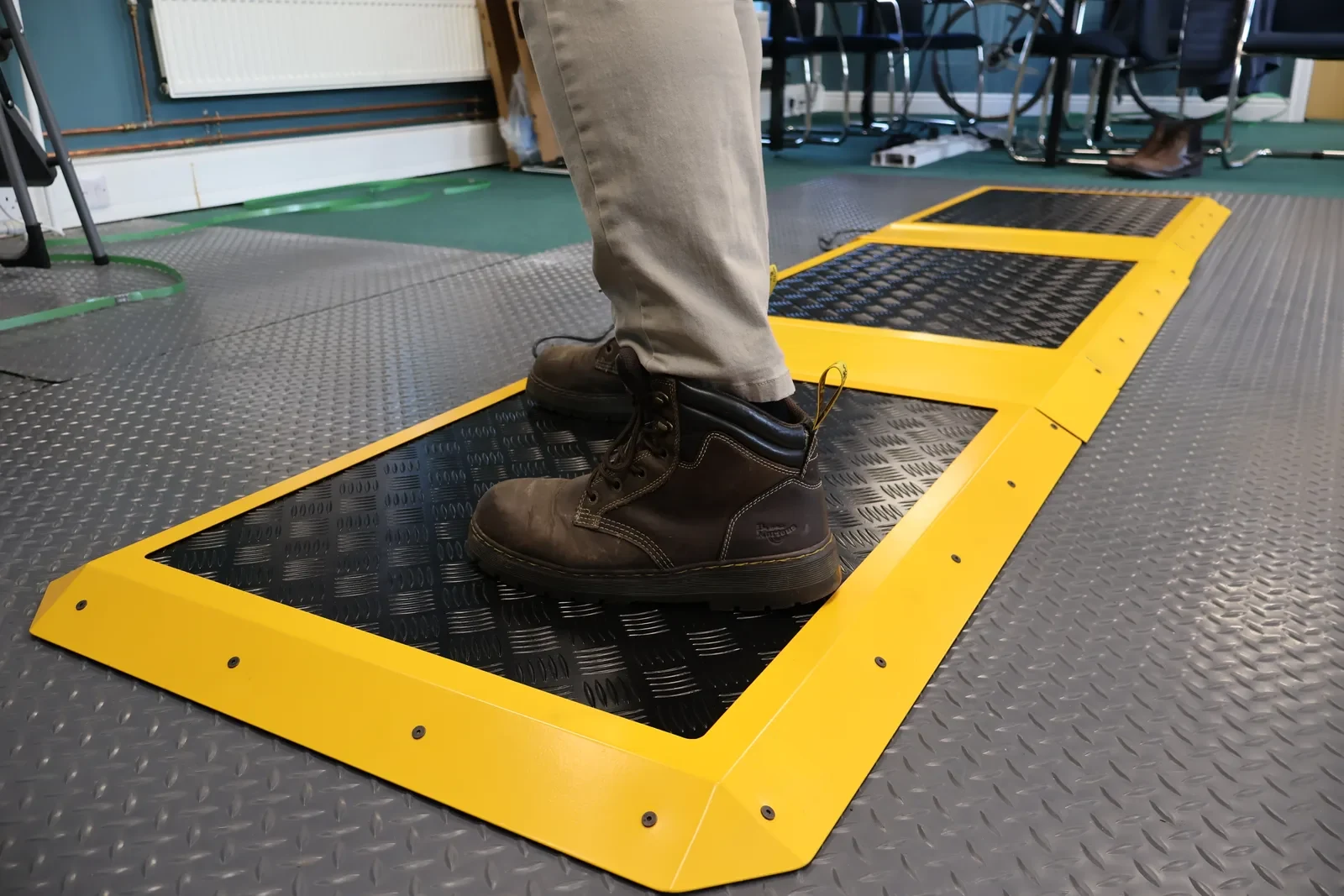 Worker in boots standing on a run of connected M-Heat heated mats